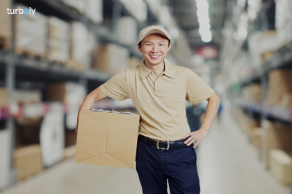 Portrait of a young warehouse worker carrying a carton box