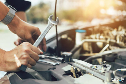 Car mechanic is holding a wrench ready to check the engine and maintenance.